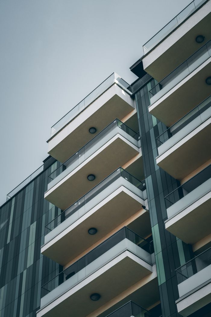 services-02 From below facade of contemporary building with geometric pattern and glass balconies against cloudless blue sky